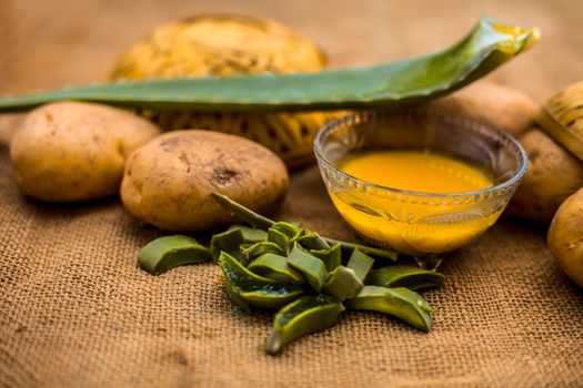 Homemade conditioner and shampoo for dandruff and scalp cleaning on jute bag's surface i.e. potato juice well mixed with aloe vera gel in a glass bowl along with raw potato and some aloe vera leaf.