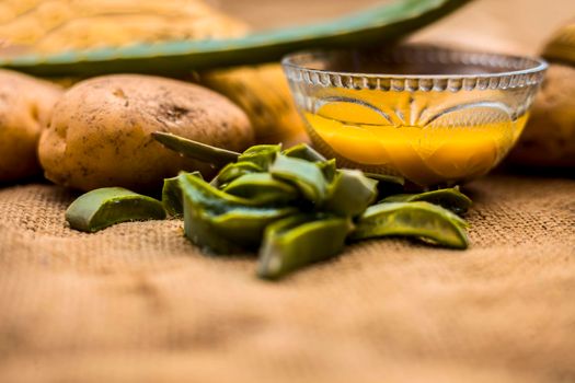 Homemade conditioner and shampoo for dandruff and scalp cleaning on jute bag's surface i.e. potato juice well mixed with aloe vera gel in a glass bowl along with raw potato and some aloe vera leaf.