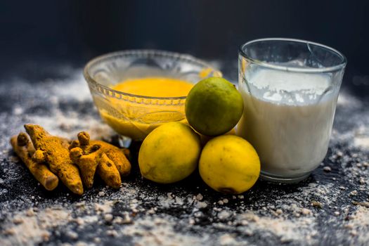 Lemon face mask on the wooden surface consisting lemon juice, gram flour or chickpea flour, turmeric or Haldi and milk in a glass bowl.For the treatment of tans.