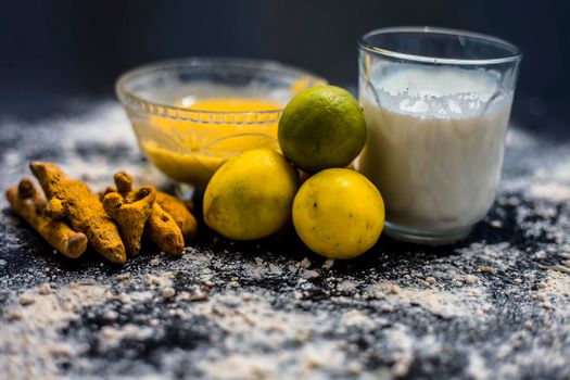 Lemon face mask on the wooden surface consisting lemon juice, gram flour or chickpea flour, turmeric or Haldi and milk in a glass bowl.For the treatment of tans.