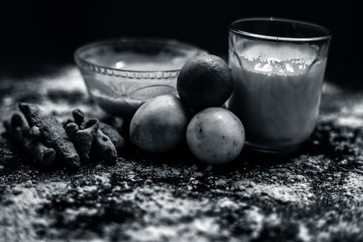 Lemon face mask on the wooden surface consisting lemon juice, gram flour or chickpea flour, turmeric or Haldi and milk in a glass bowl.For the treatment of tans.