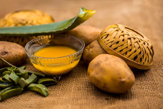 Homemade conditioner and shampoo for dandruff and scalp cleaning on jute bag's surface i.e. potato juice well mixed with aloe vera gel in a glass bowl along with raw potato and some aloe vera leaf.