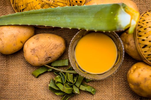 Homemade conditioner and shampoo for dandruff and scalp cleaning on jute bag's surface i.e. potato juice well mixed with aloe vera gel in a glass bowl along with raw potato and some aloe vera leaf.