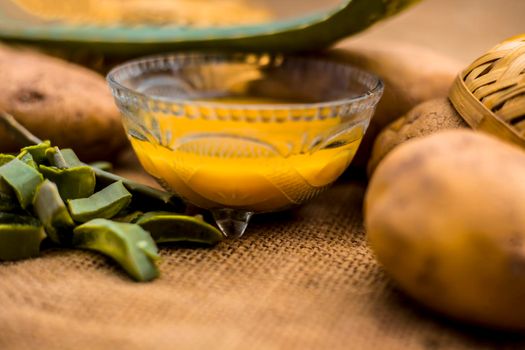 Homemade conditioner and shampoo for dandruff and scalp cleaning on jute bag's surface i.e. potato juice well mixed with aloe vera gel in a glass bowl along with raw potato and some aloe vera leaf.