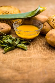 Homemade conditioner and shampoo for dandruff and scalp cleaning on jute bag's surface i.e. potato juice well mixed with aloe vera gel in a glass bowl along with raw potato and some aloe vera leaf.