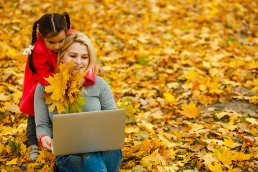 Daughter playing by herself as mother works on laptop