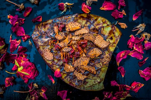 Close up of Famous Indian traditional masala pan or meetha pan on black surface with some rose water consisting of coated sauf,supari,sweeteners and some coconut powder.