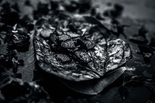 Close up of Famous Indian traditional masala pan or meetha pan on black surface with some rose water consisting of coated sauf,supari,sweeteners and some coconut powder.