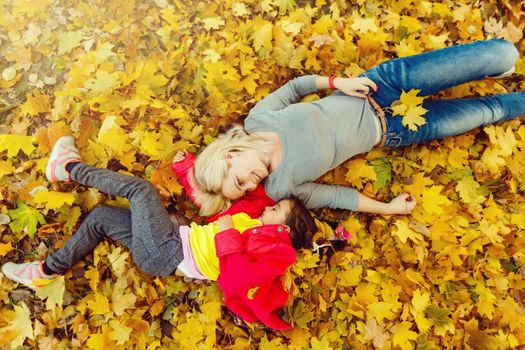 Mother and daughter in autumn yellow park.