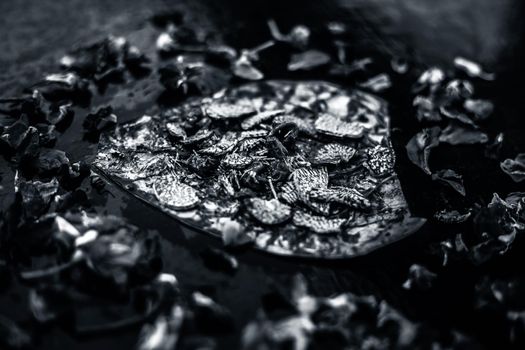 Close up of Famous Indian traditional masala pan or meetha pan on black surface with some rose water consisting of coated sauf,supari,sweeteners and some coconut powder.