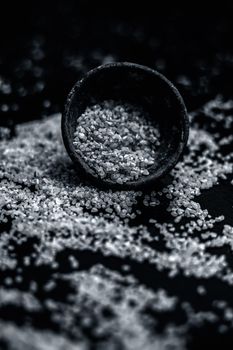 Raw oats in a black colored clay bowl on the black surface.