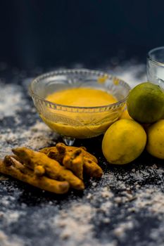 Lemon face mask on the wooden surface consisting lemon juice, gram flour or chickpea flour, turmeric or Haldi and milk in a glass bowl.For the treatment of tans.