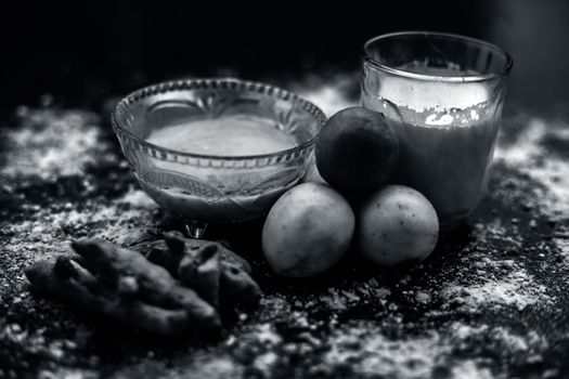 Lemon face mask on the wooden surface consisting lemon juice, gram flour or chickpea flour, turmeric or Haldi and milk in a glass bowl.For the treatment of tans.