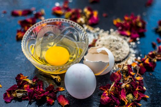 Egg and besan or chickpea flour or gram flour on wooden surface in a glass bowl along with raw egg and flour on the surface.For the treatment of lines and wrinkles.