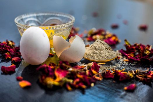 Egg and besan or chickpea flour or gram flour on wooden surface in a glass bowl along with raw egg and flour on the surface.For the treatment of lines and wrinkles.