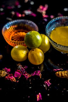 Face mask of lemon juice, honey, and curd along with some raw turmeric well mixed in a glass bowl along with entire raw ingredients on the wooden surface for acne-prone skin and blemishes.