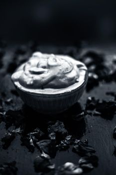 Ubtan/face mask/face pack of Multani mitti or fuller's earth on wooden surface in a glass bowl consisting of Multani mitti and rose water for the remedy or treatment of oily skin.On wooden surface.