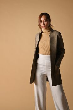 Portrait of tendy woman wiith trench coat standing on beige background. Fashion studio photo, Autumn and Winter concept.