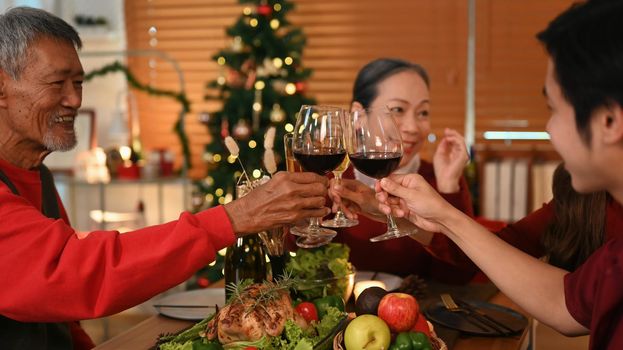 Young coupler celebrating Christmas or New Year with grandparents and clinking glass of wine. Christmas and thanksgiving concept.