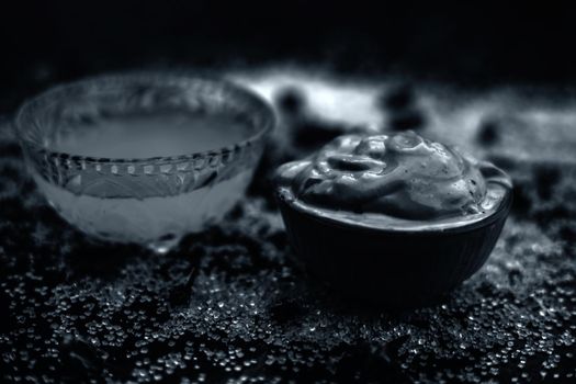 Ubtan/face mask/face pack of Multani mitti or fuller's earth on wooden surface in a glass bowl consisting of Multani mitti and coconut oil for the remedy or treatment of suntan.On the wooden surface.