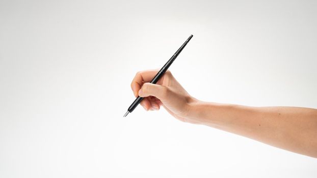 A woman's right hand holds a pen for calligraphy and writing gesture to write. High quality photo