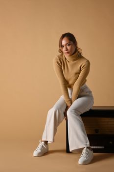 Portrait of tendy woman in autumn outfit posing on beige background. Fashion studio photo, Autumn and Winter concept.