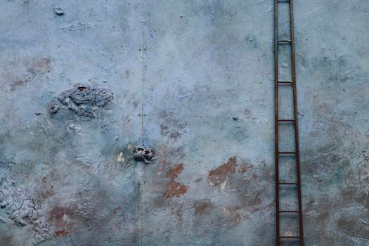 Minimalist picture showing a textured blue wall and a narrow ladder