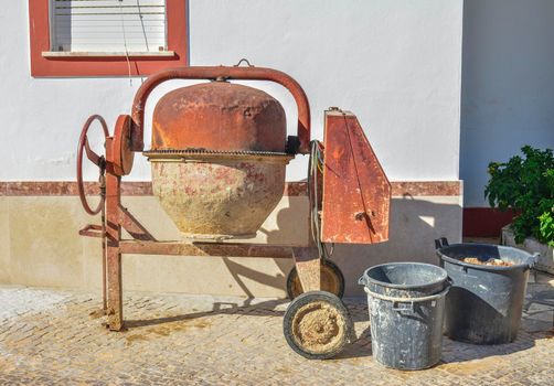 Old rusty manual mixer machine near the house