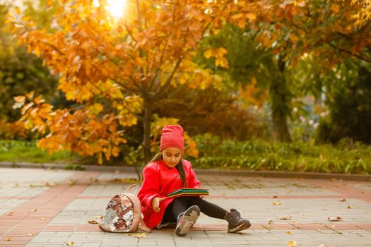 Little cute girl in autumn park. Schoolgirl with a backpack.The concept of autumn, school, study, education, childhood, back to school.