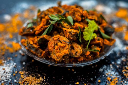 Famous Indian & Gujarati snack dish in a glass plate on wooden surface i.e. Patra or paatra consisting of mainly Colocasia esculenta or arbi ke pan or elephant ear leaves and spices. Horizontal shot.