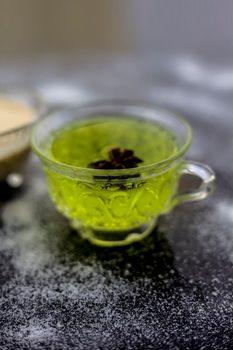 Rice flour and rice grain on wooden surface along with some green tea in a transparent glass cup and a star anise in it.Face mask for the treatment for smoother skin.