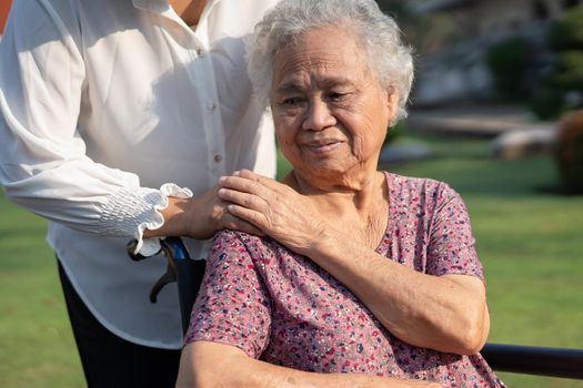 Caregiver help and care Asian senior or elderly old lady woman patient sitting on wheelchair in park, healthy strong medical concept.