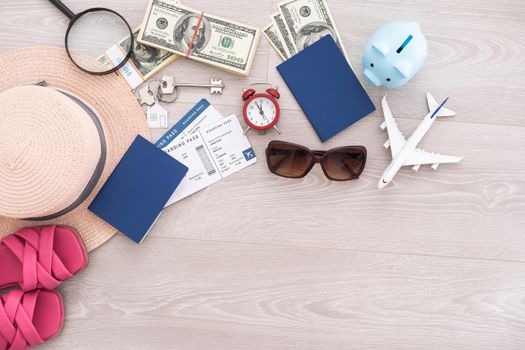 A piggy bank with dollar bills in a travel setting. In the composition of the image: Sun Hat, Alarm Clock. Concept of saving money for traveling on vacation