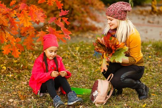 Mom leads her daughter to school. Return to school. Woman and girl with backpack behind the back. Beginning of lessons. First day of fall.