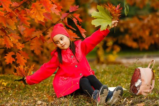 Pupil of primary school with book in hand. Girl with backpack near building outdoors. Beginning of lessons. First day of fall.