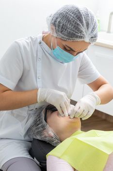 Patient with cheek retractor lying in dentist office in modern clinic