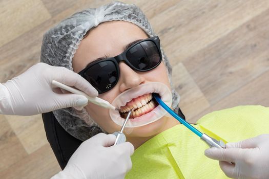 Patient with cheek retractor lying in dentist office in modern clinic