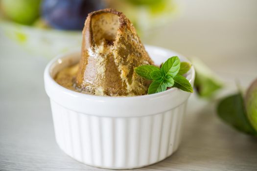 pear baked in curd dough in a small ceramic form, on a wooden table.