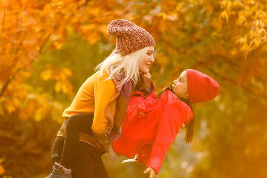 portrait of a young woman and her daughter in the autumn park