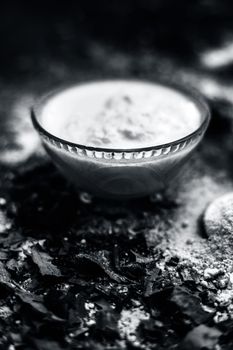 Neem or Indian Lilac face mask on the black wooden surface for acne and scars consisting of gram flour, neem paste, and some curd.