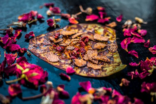 Close up of Famous Indian traditional masala pan or meetha pan on black surface with some rose water consisting of coated sauf,supari,sweeteners and some coconut powder.