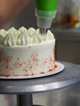 hand pof chef making for icing a red drip cake in the professional kitchen lab