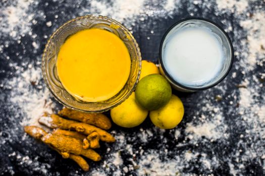 Lemon face mask on the wooden surface consisting lemon juice, gram flour or chickpea flour, turmeric or Haldi and milk in a glass bowl.For the treatment of tans.