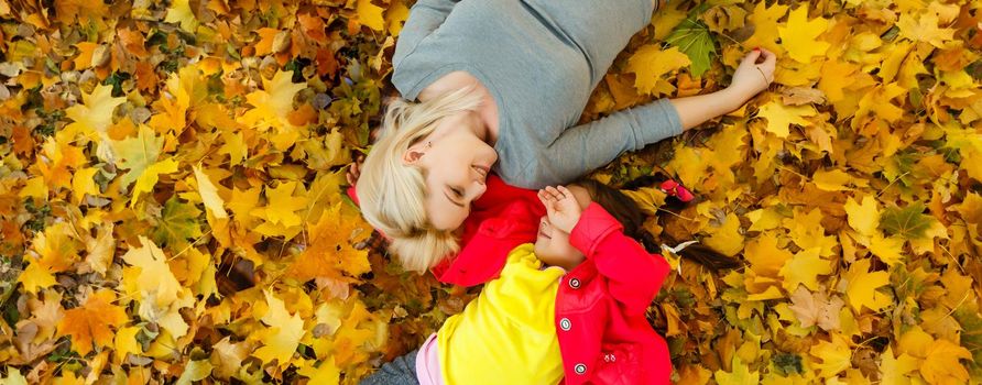 Mother and daughter in autumn yellow park.