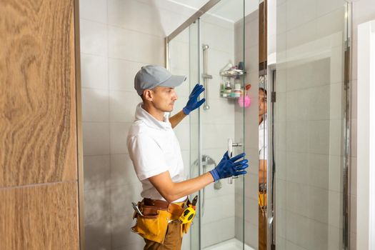 Plumber installing shower stall, work in bathroom