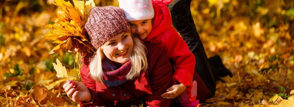 happy family: mother and child little daughter play cuddling on autumn walk in nature outdoors