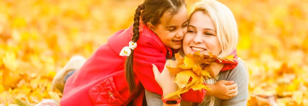 Young mother playing with her daughter in autumn park