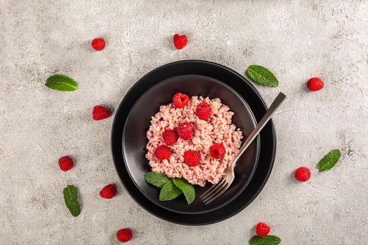 Healthy food on gray concrete background. Fresh raspberries risotto on a delicate and elegant dish