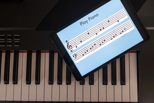 Piano synthesizer app on tablet and musical instrument concept.