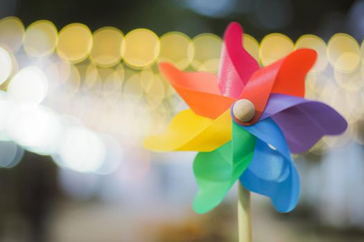 Colorful pinwheel with golden bokeh background. Toy for education nature phenomenon.